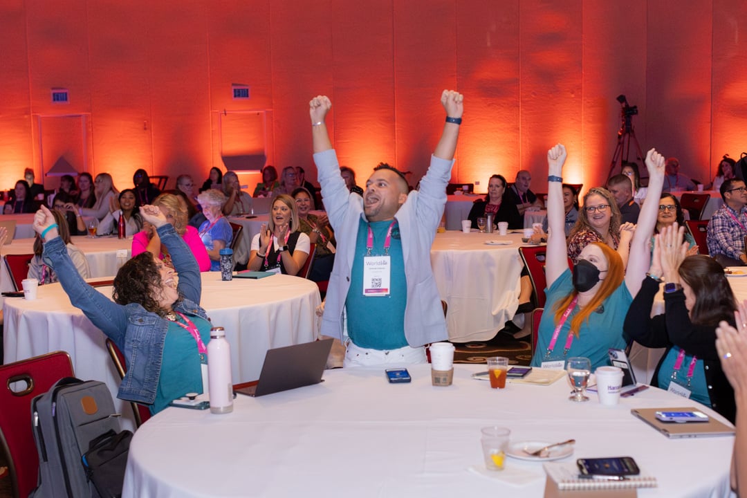 Guests raising their hands in excitement in the audience