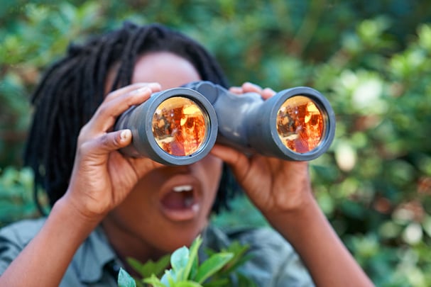 A young boy looking through his binoculars