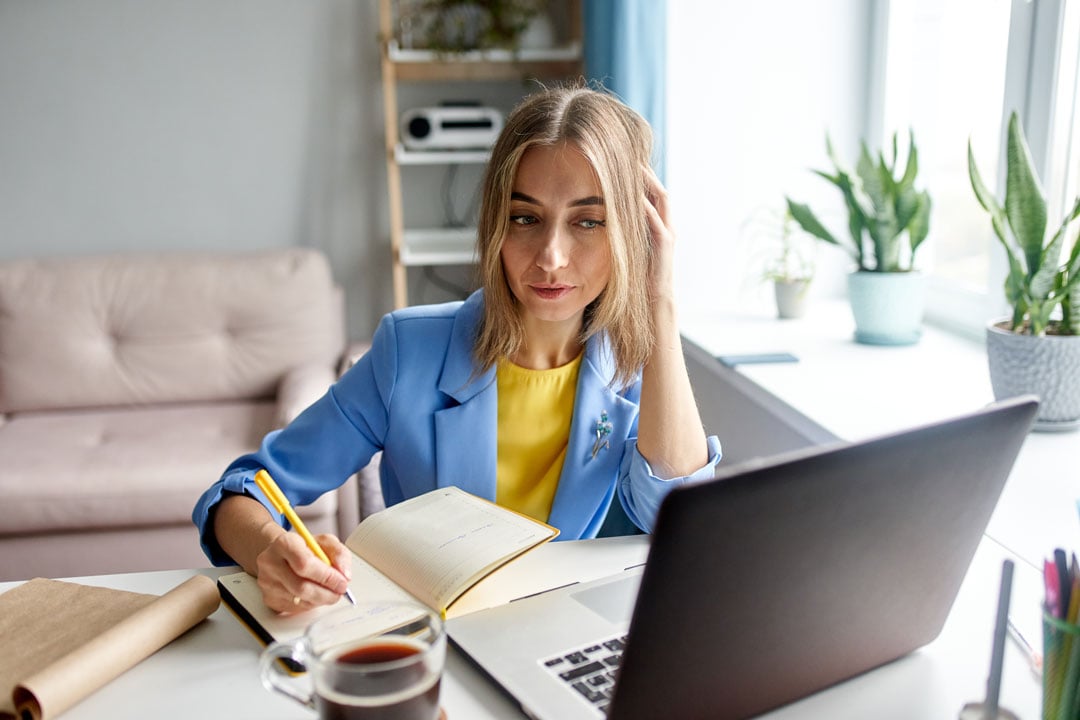 Woman Working from Home with Laptop and Notepad
