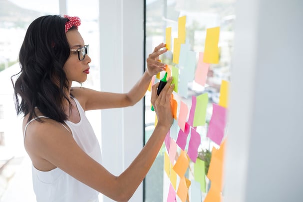 Woman with Sticky Notes Brainstorming on Glass Wall