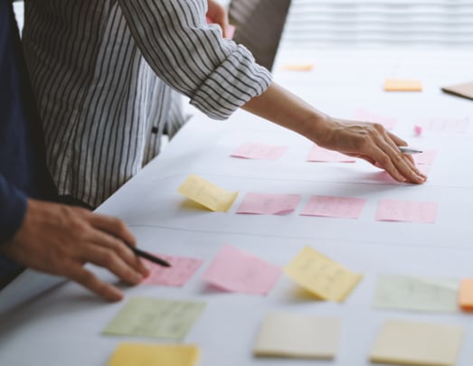 Man and woman using sticky notes and writing on them to make a plan for their business
