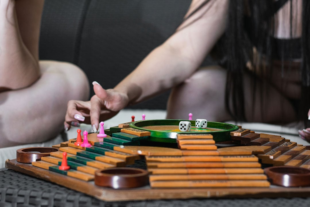shot of the hands of two friends as they move their game pieces on the Parques board