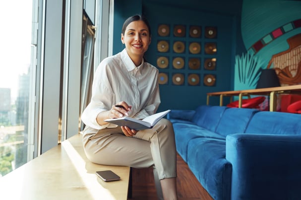 Stylish Woman Writes in Notebook by Window