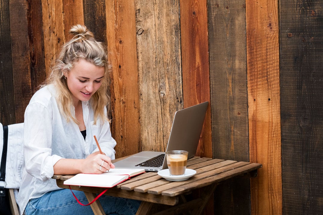 woman sitting alone at a cafe table working outdoors