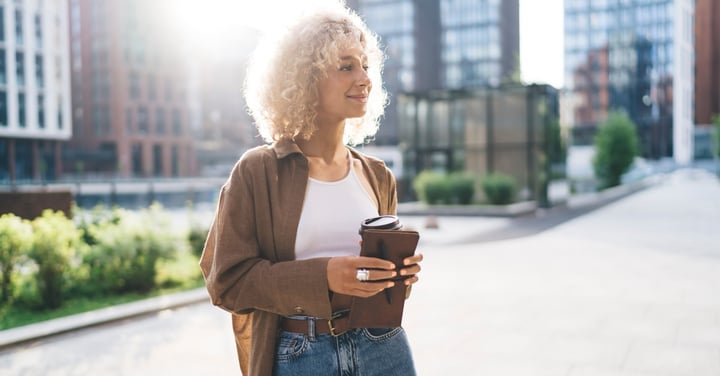 Stylish woman holding coffee in urban setting