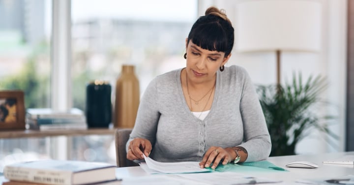 Woman reviews documents at desk in bright room