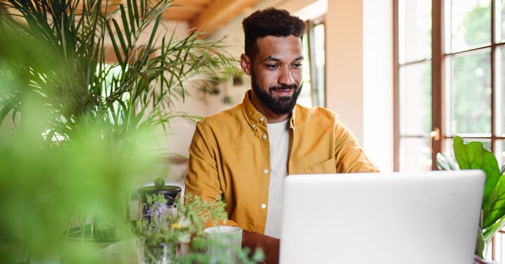 Man working at home with laptop and plants