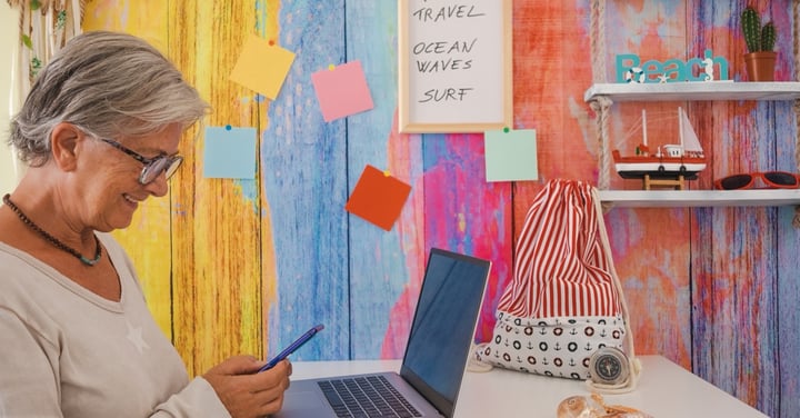 Senior woman planning vacation at home with laptop