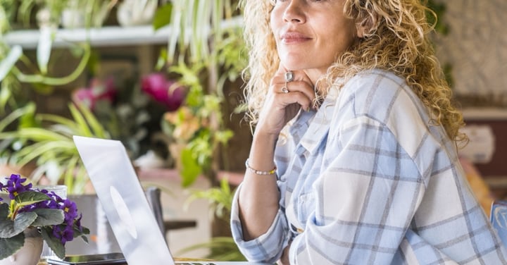 Woman working on laptop surrounded by plants