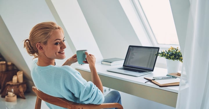Woman at desk with laptop enjoying coffee