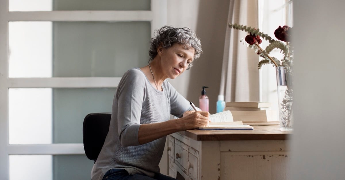 Senior woman writing in a journal at a wooden desk