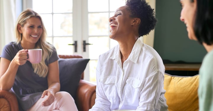 Three women friends laughing together at home