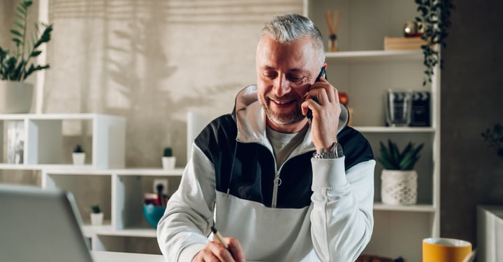 Man on phone taking notes at desk