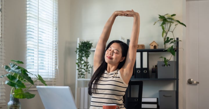 Woman stretching at desk in home office