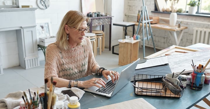 Woman working on laptop in bright art studio