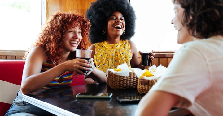 Three young women laughing together in a retro diner
