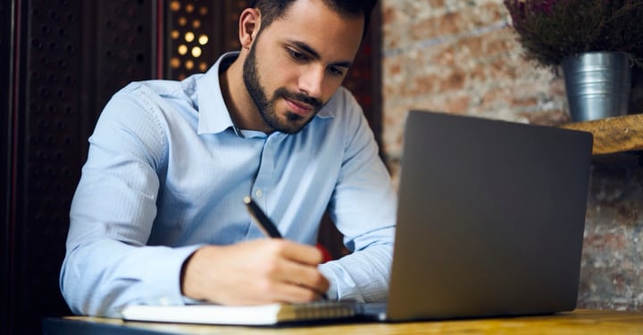 Focused man working with laptop and notepad