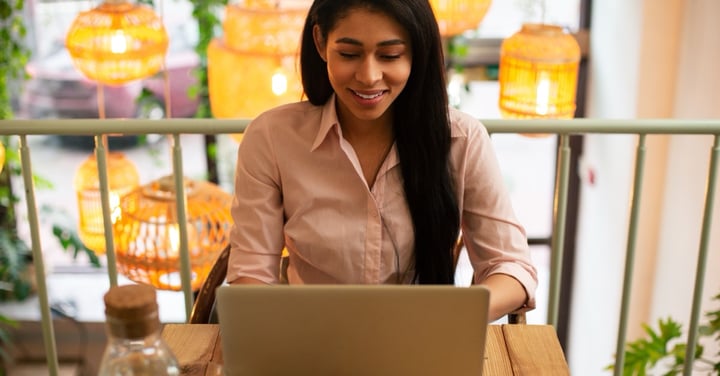 Cheerful woman working on laptop in cafe