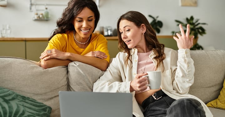 Two young women relaxing at home with laptop