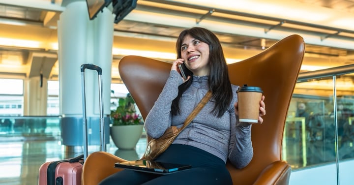 Smiling woman traveler talking on phone in airport lounge