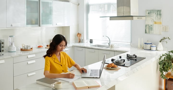 Woman working at kitchen island with laptop