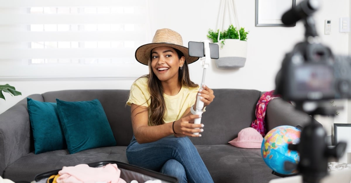 Smiling woman records travel video on living room couch