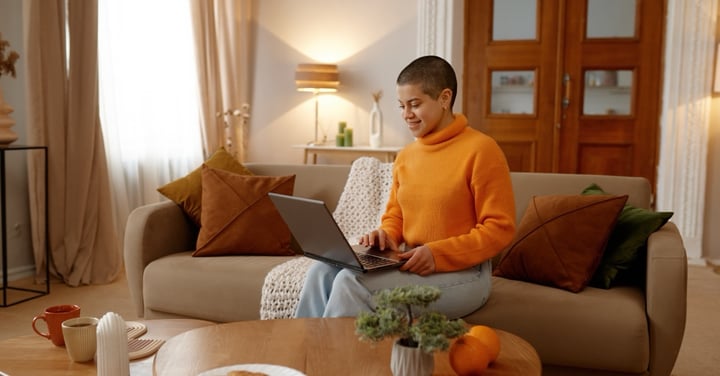 Woman using laptop on couch in bright living room