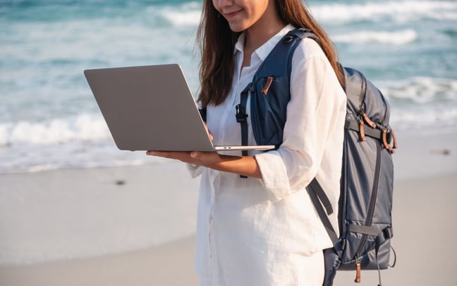 Closeup Of A Female Traveler Using And Working On Laptop Computer While Walking On The Beach