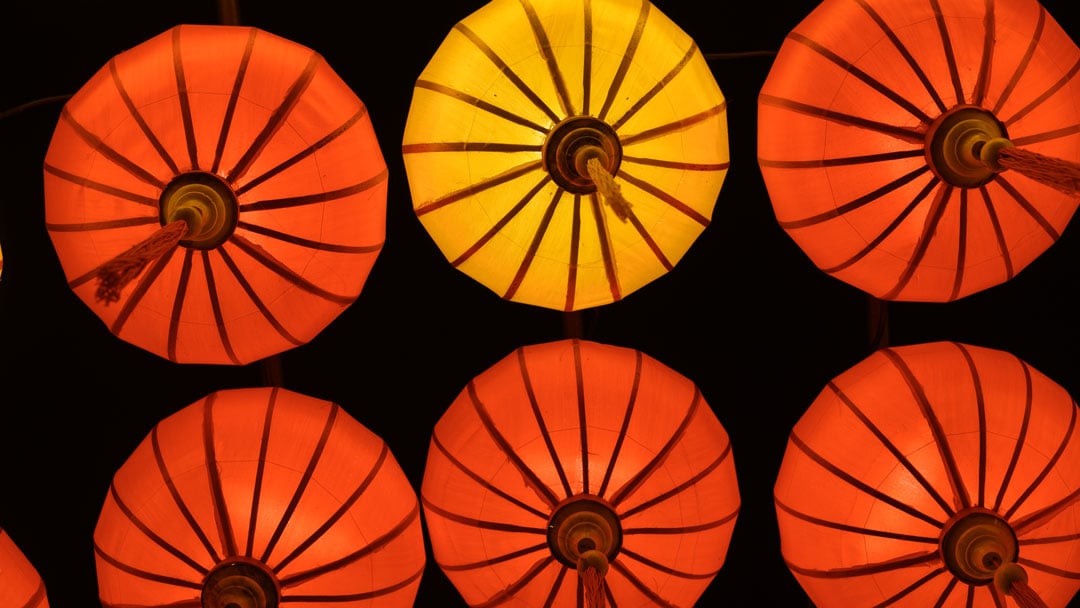 Low angle of red and orange sky lanterns flying up at night