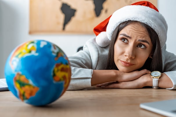 Travel advisor stressed with Santa hat looking at a globe