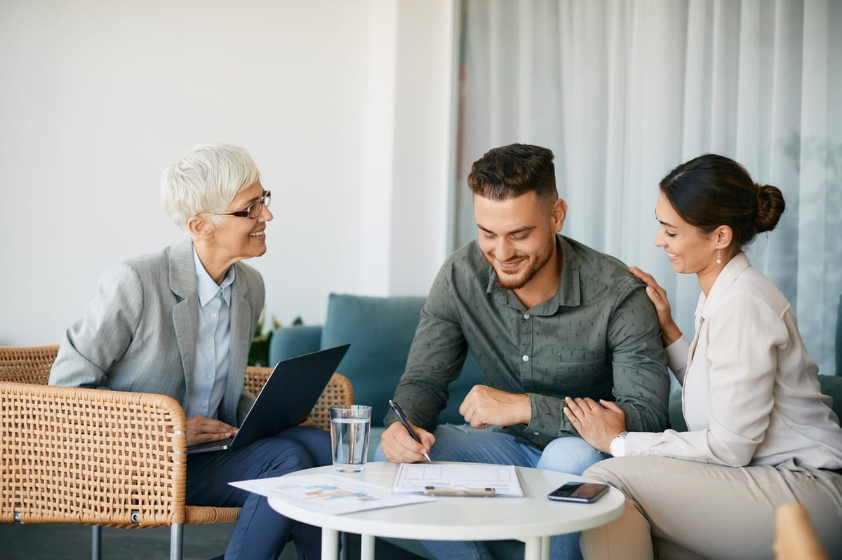 Travel advisor meeting with a smiling couple as they sign their travel plans