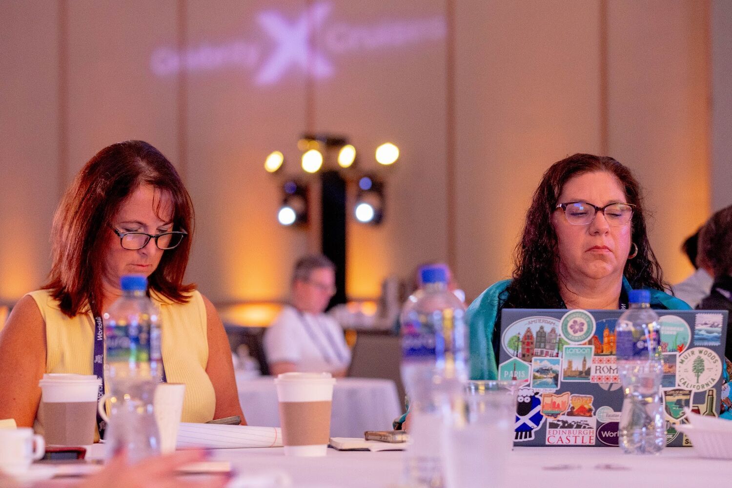 Two advisors at a table with coffee and laptops, concentrating during a partner education session