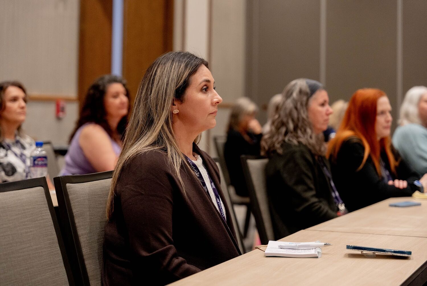 A row of advisors seated shoulder to shoulder at a classroom table, focused on the speaker