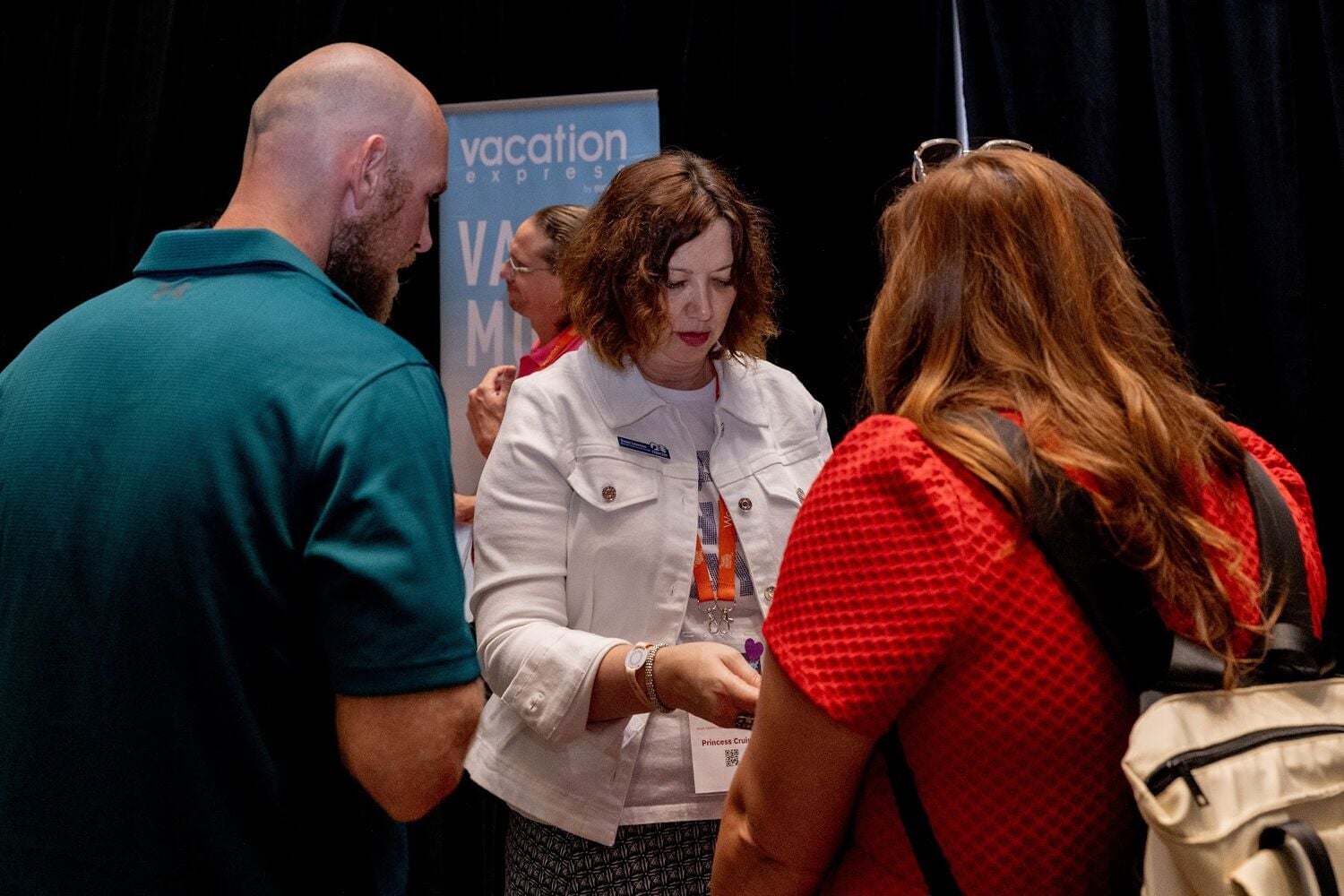Two advisors talking with a supplier partner in front of a partner banner
