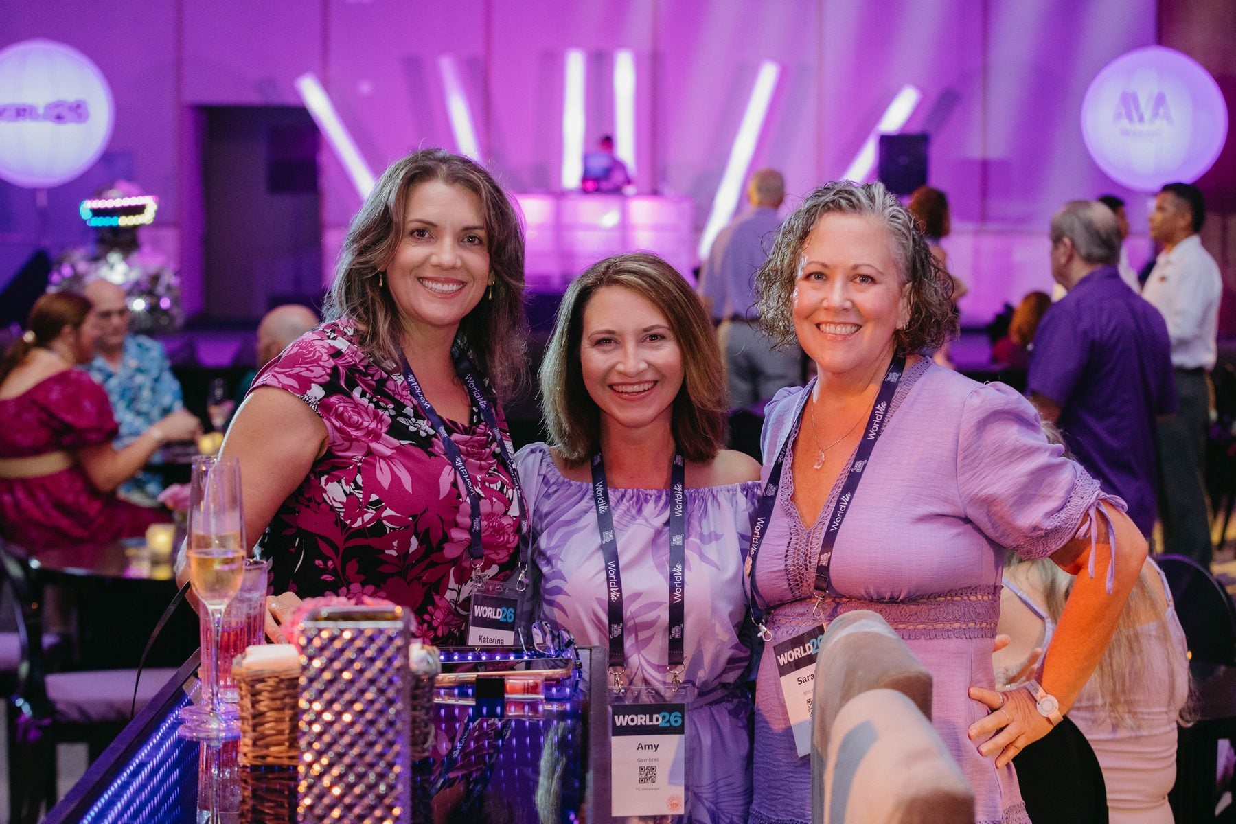 Three members smiling together at the WORLD26 Purple Party